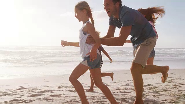 暑假在海滩上追逐孩子的父母视频素材