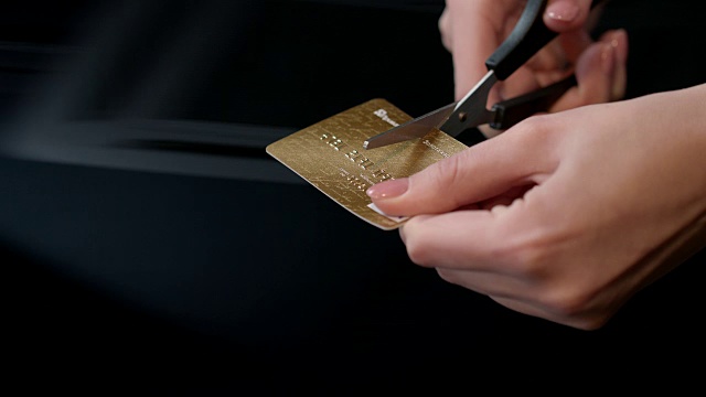 女性的手正在用剪刀剪信用卡。借记卡结账视频素材