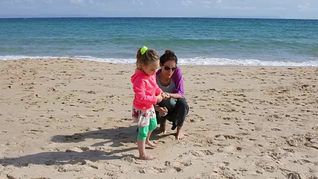 女孩和妈妈在海滩上捡贝壳视频下载