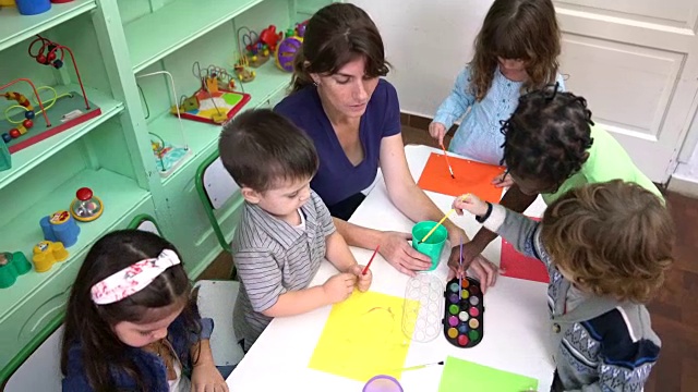 幼儿园的孩子在教室里和老师一起画画视频下载