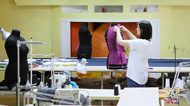 年轻女性时装设计师工作室作品。服装设计师正在测量人体模型视频素材