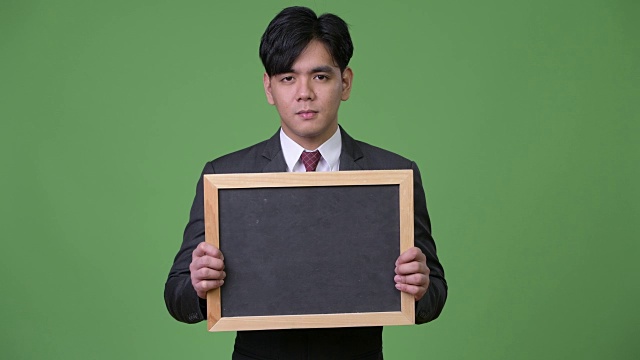 年轻英俊的亚洲商人展示黑板视频下载