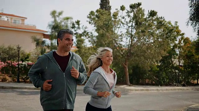 一对活跃的成熟夫妇在春天一起在郊区的街道上慢跑视频素材