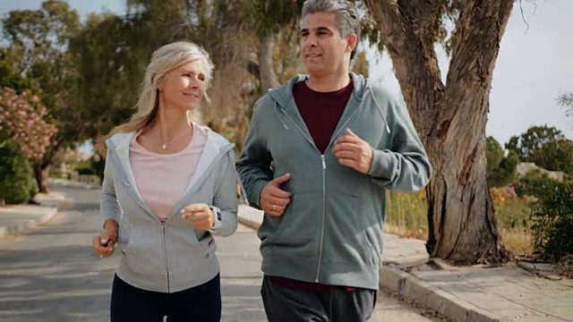 快乐成熟的夫妇一起慢跑在阳光明媚的春天视频素材