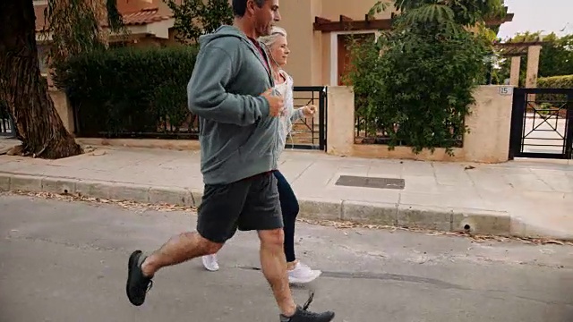 多民族的老年夫妇在郊区的街道上一起锻炼和慢跑视频素材