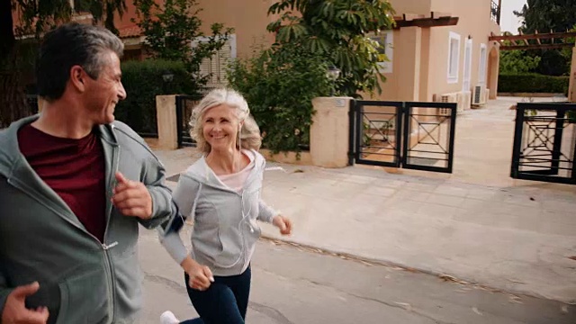 一对快乐的多民族成熟夫妇在郊区的街道上一起慢跑视频素材