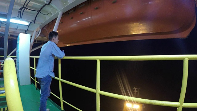 夜晚，人们站在海上石油平台上眺望大海。视频下载