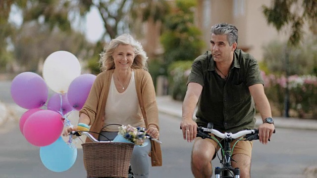 快乐的成熟夫妇在浪漫的约会中一起骑自行车视频素材