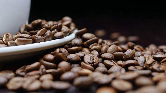 一杯热咖啡和烘豆周围在4k分辨率的黑色背景慢动作视频下载