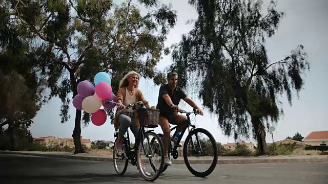 浪漫的多民族成熟夫妇在春天一起骑自行车视频素材