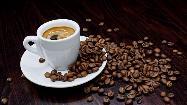一杯热咖啡和烘豆周围在4k分辨率的黑色背景慢动作视频下载
