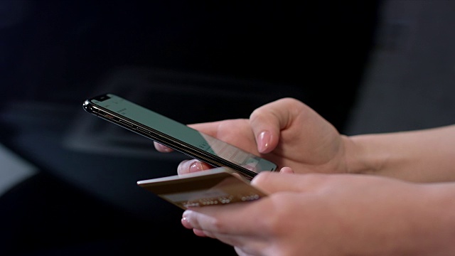 女性手持信用卡，使用智能手机进行网上购物视频素材