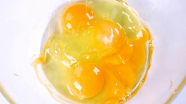 新鲜有机鸡蛋落入玻璃碗中的慢动作视频素材