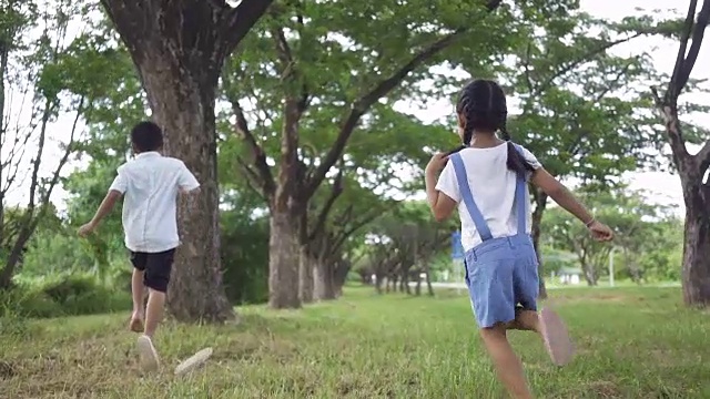 慢镜头，亚洲家庭，男孩和女孩在公园里跑步。视频素材