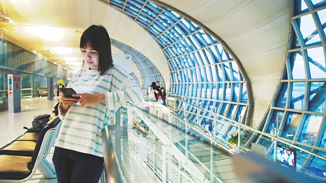亚洲女性游客在机场使用电话视频下载