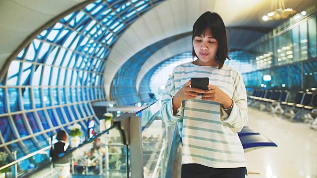 亚洲女性游客在机场使用电话视频下载