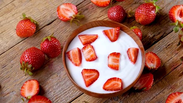 草莓酸奶在木碗桌上旋转视频素材