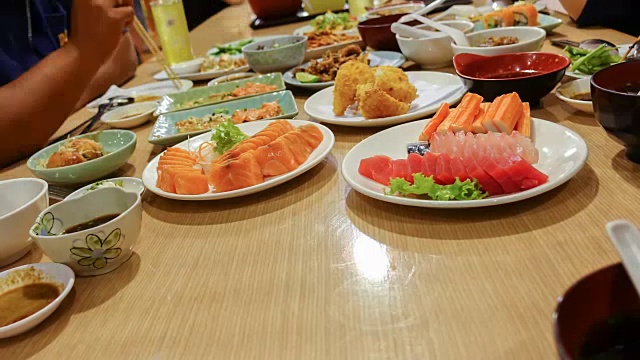 在一家日本餐馆里，一群朋友用筷子吃寿司。视频素材