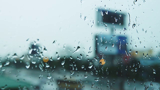 4K:雨滴落在窗玻璃上，交通背景中的建筑物视频素材