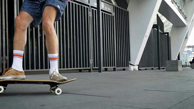 男腿做花样，奥利在滑板上，滑板者的脚在城市溜冰时，从侧面观看视频素材