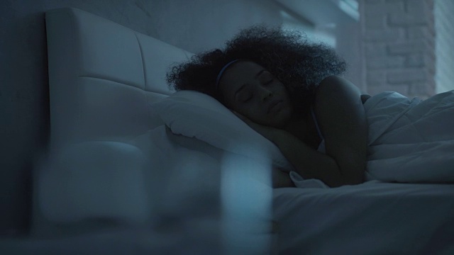 美丽的黑人女孩晚上在床上睡觉视频素材