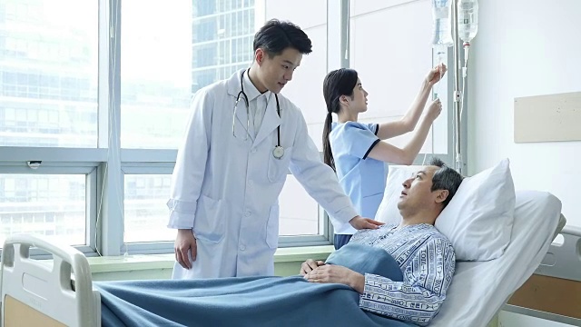 医生在病床上和病人说话，护士正在挂点滴袋视频素材