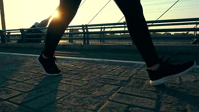 在阳光下的桥上行走的人的腿视频素材