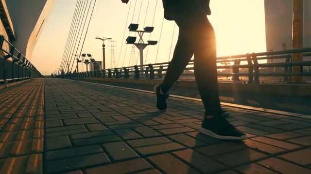 在阳光下的桥上行走的人的腿视频素材