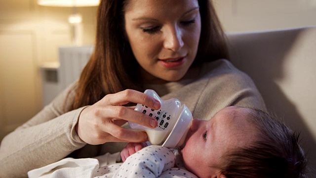 母亲在托儿所用奶瓶喂养新生儿视频素材