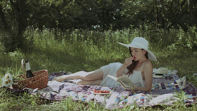 优雅的女人在夏天的公园里看书视频素材