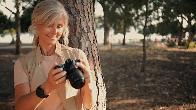 时尚的高级女性在公园里用相机拍照视频素材