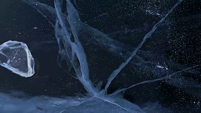 戴手套的人在冰上拧冰。缓慢的运动。镜头移到了冰的后面。一块美丽的冰在冰上旋转，有神奇的裂缝。视频素材