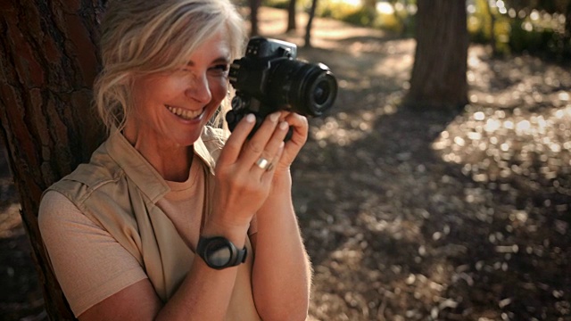 快乐成熟的女性旅行者在森林里用相机拍照视频素材