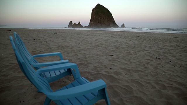 干草堆岩石和甲板椅子，Cannon海滩黎明4K。UHD视频下载