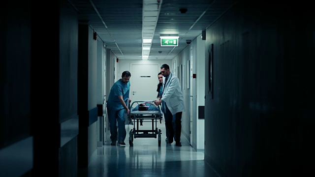 急诊科:医生，护士和护理人员跑和推轮床/担架与严重受伤的病人走向手术室。明亮的现代医院，专业人员挽救生命。视频下载