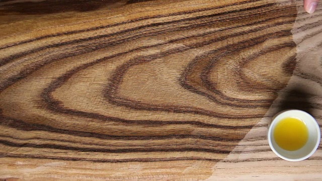 木材浸渍处理以保护。女手用海绵、刷子将亚麻籽油涂在木板上。切菜板制造。防水生态，健康安全。视频下载