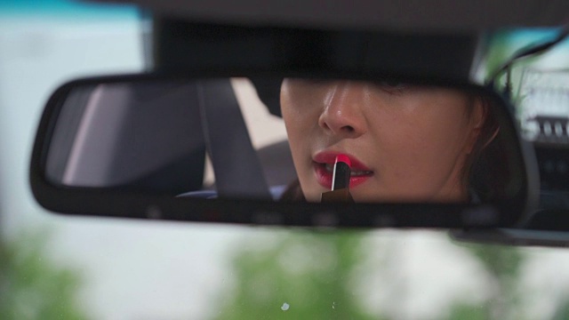 一个女人在车里用后视镜涂口红视频素材