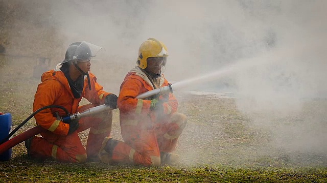 消防队员在一次灭火行动中，用高压喷嘴将泡沫喷向发生火灾的卡车视频素材