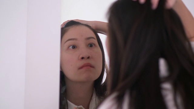 一名泰国妇女正在镜子旁挤她脸上和嘴上的痘痘视频下载