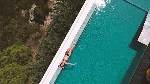 鸟瞰图，一个女人日光浴的无边泳池视频素材