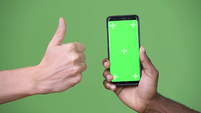 两只不同种族的手在竖起大拇指的同时展示手机视频素材