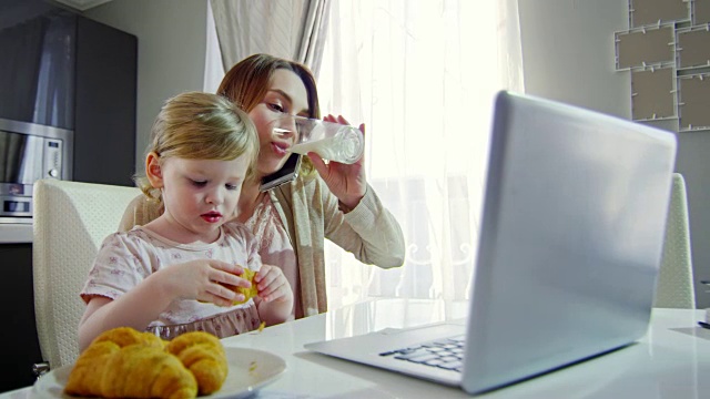 蹒跚学步的孩子和在家工作的妈妈一起吃早餐视频素材