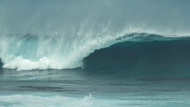 慢镜头:惊心动魄的蓝色桶状波浪冲击着充满异国情调的海岸。视频素材
