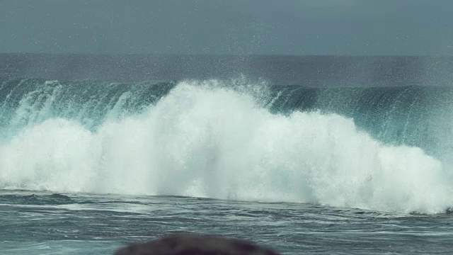 慢动作:巨大的玻璃般的海浪溅向遥远的热带岛屿。视频素材