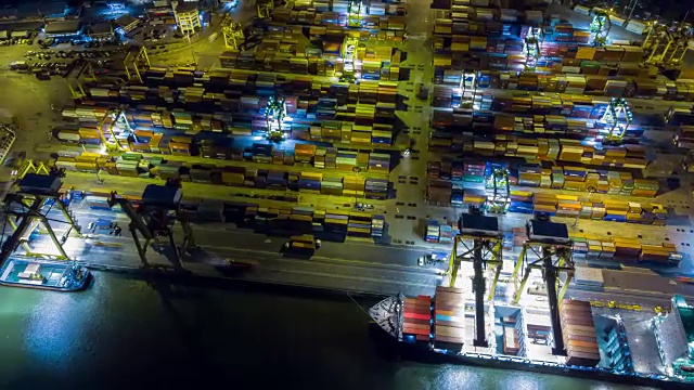鸟瞰图无人机延时或超延时在泰国曼谷的工业港口与许多集装箱船船和大型起重机在夜间工作。视频素材