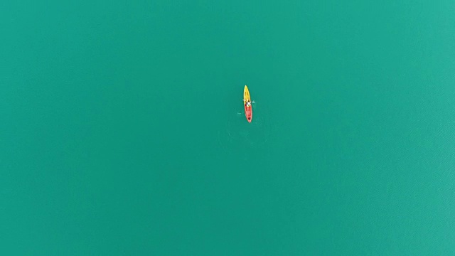 4k鸟瞰图和平坦的躺在湖中独自一人皮划艇。视频下载