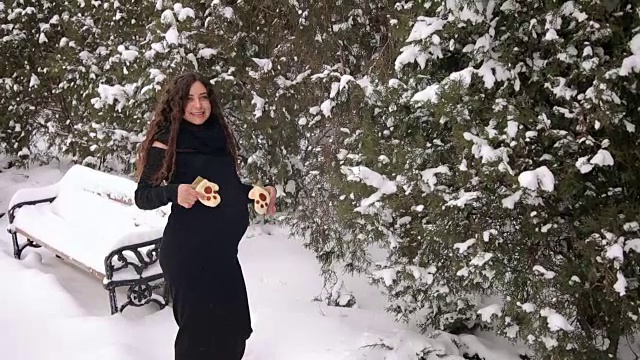 一个怀孕女孩在一个公园里的肖像在一个降雪。视频素材