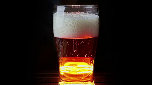 新鲜的啤酒与泡沫进入饮料品脱玻璃杯与冰冻滴，在金棕色的背景，有趣和营养的食品和饮料概念视频下载
