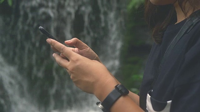 Cu:游客在瀑布边使用智能手机视频素材