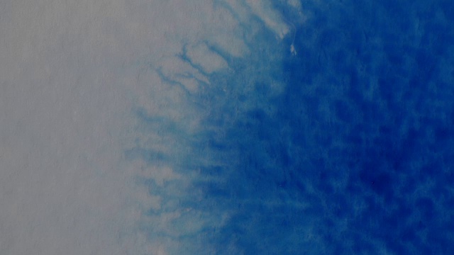蓝色墨水滴在潮湿的水彩纸上的特写。视频下载